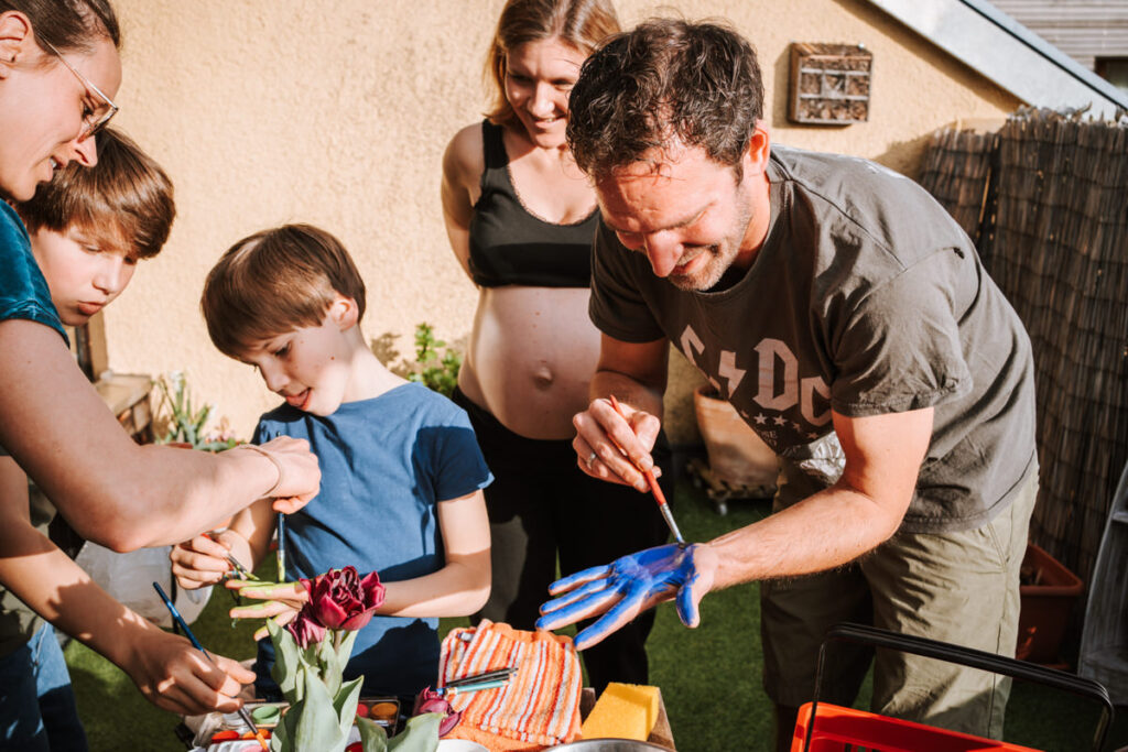 Familie-mit-Kindern-beim-Babybauch-bemalen
