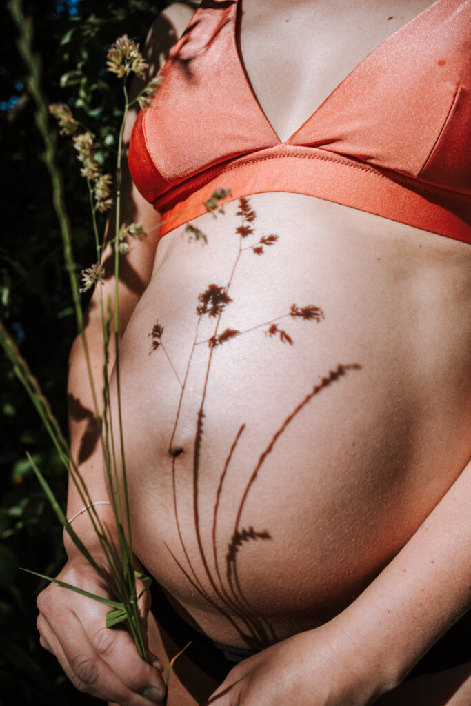 Schwangerer-Bauch-in-Bikini-mit-Schattenspiel-von-Blumen
