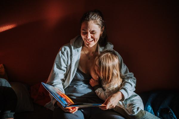 Mutter stillt Kleinkind und liest vor