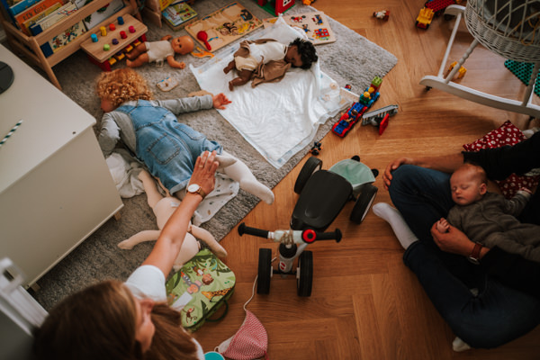 Eltern mit Kleinkind und Baby im Kinderzimmerchaos