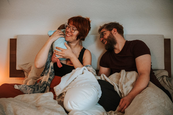 Glückliche Eltern mit Baby im Bett