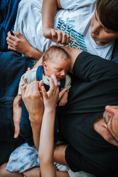 Vater und Brüder halten Baby und streicheln sein Gesicht