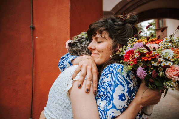 Freundinnen mit Brautstrauß umarmen sich nach standesamtlicher Hochzeit in Freiburg