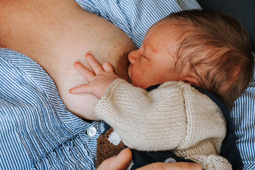 Nahaufnahme. Baby stillt und hat seine Hand auf der Brust abgelegt.