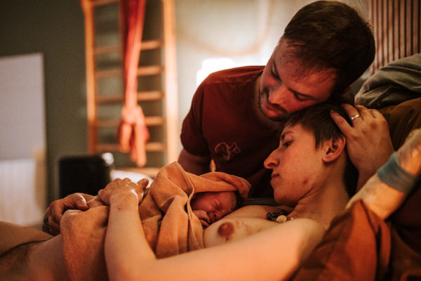 Mama und Papa kuscheln direkt nach der Geburt im Geburtshaus mit Baby
